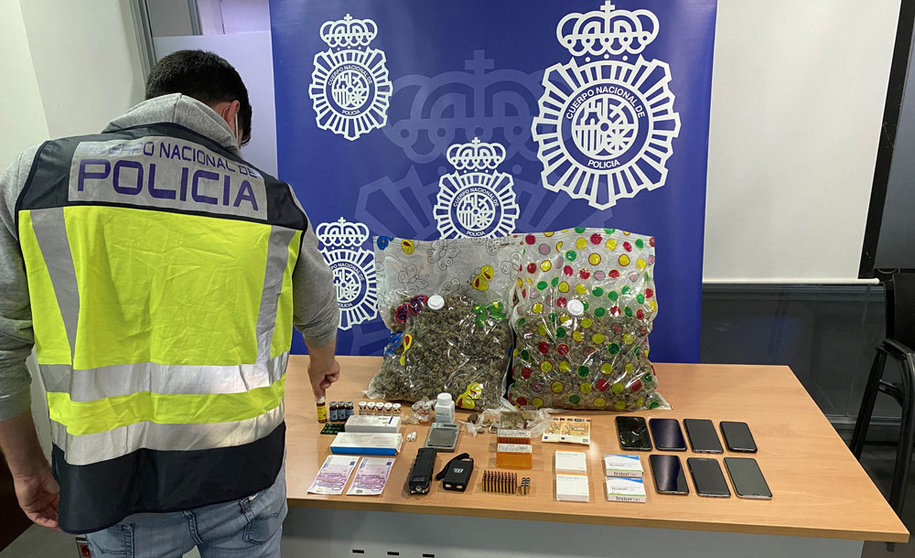 An agent of the National Police, next to the drugs and other materials seized during the house search. Photo: Policia Nacional.