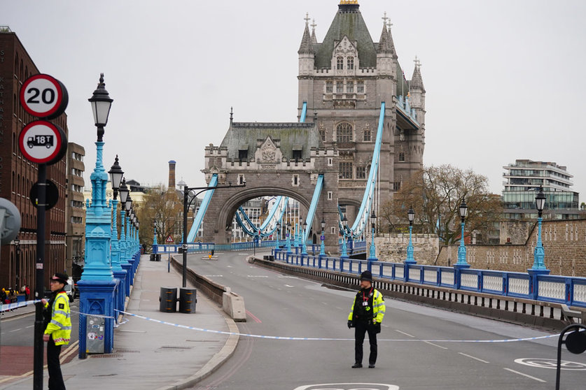 08 April 2022, United Kingdom, London: Police officers block access to Tower Bridge, east London, as activists from Extinction Rebellion hang from suspension cords beside a giant banner that reads "End fossil fuels now", as they stage a protest which has closed the bridge to traffic. Photo: Victoria Jones/PA Wire/dpa.