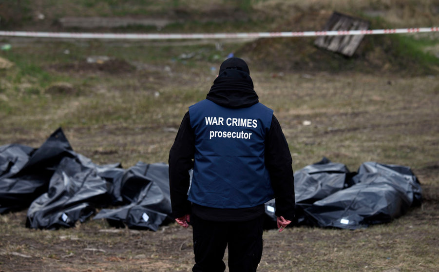 11 April 2022, Ukraine, Butscha: An investigator wears a vest labeled "War Crimes Prosecutor" and begins collecting evidence of war crimes alongside bodies from a mass grave behind St. Andrew's Church. Photo: Carol Guzy/ZUMA Press Wire/dpa.
