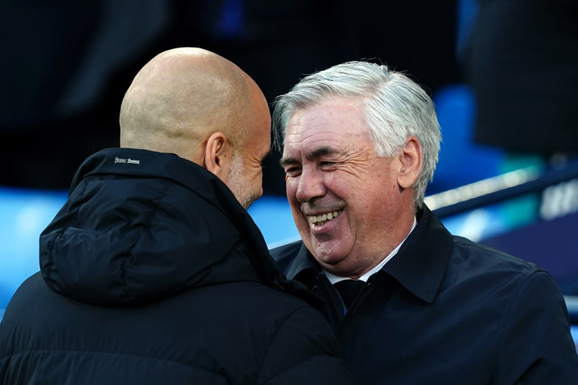 26 April 2022, United Kingdom, Manchester: Real Madrid manager Carlo Ancelotti and Manchester City manager Pep Guardiola greet each other before the start of the UEFA Champions League Semi Final, First Leg, soccer match between Manchester City and Real Madrid at the Etihad Stadium. Photo: Martin Rickett/PA Wire/dpa.