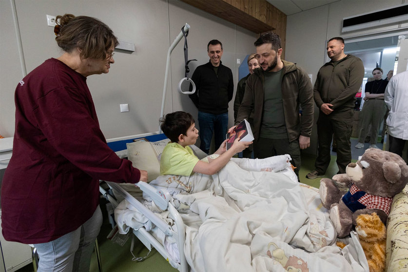 HANDOUT - 26 April 2022, Ukraine, Kiev: Ukrainian President Volodymyr Zelensky (C) gives an iPad to Ilya Matvienko, who is being treated at Okhmatdyt National Children's Specialized Hospital in Kiev. The boy is one of two orphans evacuated during the Russian attack on the city of Mariupol. Photo: Ukraine Presidency/Planet Pix via ZUMA Press Wire/dpa.