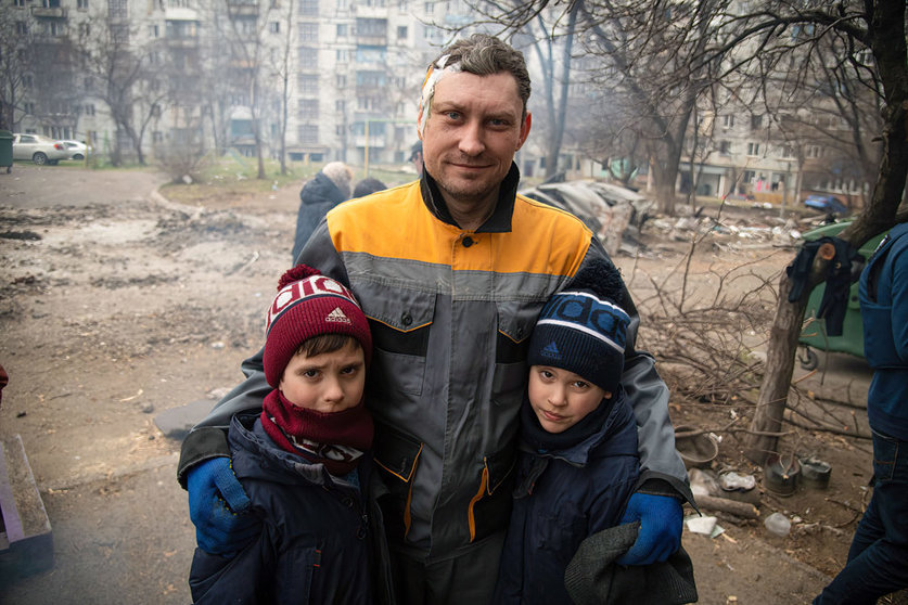 03 April 2022, Ukraine, Mariupol: A wounded man stands with his children in a destroyed neighbourhood in Mariupol during Russia's invasion of Ukraine. By capturing the Ukrainian port city of Mariupol, Russia says it wants to create a secure land link to the annexed Black Sea peninsula of Crimea. Photo: Maximilian Clarke/SOPA Images via ZUMA Press Wire/dpa.