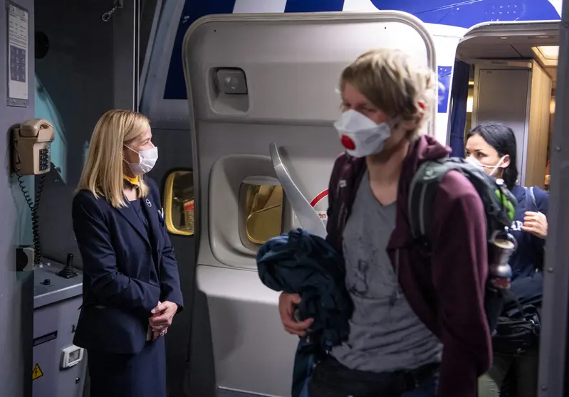 FILED - 08 April 2020, Frankfurt_Main: A flight attendant and passengers are seen wearing face masks after landing by Lufthansa's Boeing 747 at Frankfurt Airport. The EU has announced the relaxing of anti-Covid measures for air travellers, dropping the recommendation to wear masks in airports and on aircraft from Monday, the European Aviation Safety Agency (EASA) and the EU health authority ECDC said Wednesday. Photo: Boris Roessler/dpa.