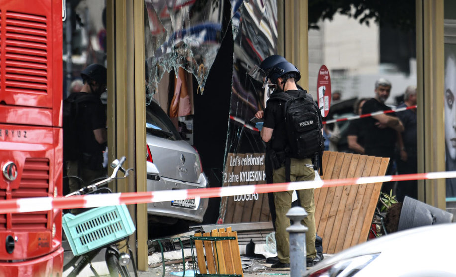 08 June 2022, Berlin: Police secure traces on a broken shop window where a car, stuck inside the shop, crashed into a group of people in Berlin. According to the fire brigade, one person was killed and at least eight injured on Wednesday morning. Photo: Fabian Sommer/dpa.