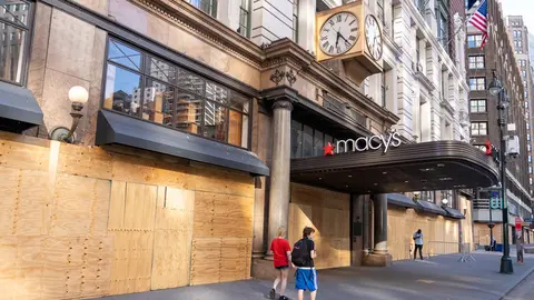 People walk by a boarded up Macy's flagship store in Herald Square on the first day of the city reopening. Photo: Ron Adar/SOPA Images via ZUMA Wire/dpa