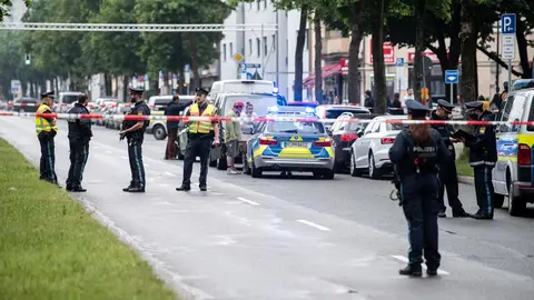 10 June 2020, Bavaria, Munich: Police officers stand near the scene, where a vehicle drove into a group of people. The car passengers then attacked the group they had driven into. Three were injured, either from the impact or in the subsequent brawl. Photo: Matthias Balk/dpa