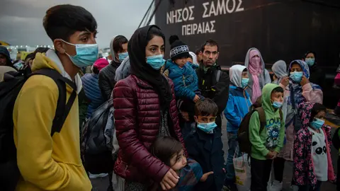 Migrants with face masks from the Moria camp, who arrived by ship from the island of Lesbos, stand in the port of Piraeus near Athens after their arrival. Greek authorities transferred some 400 migrants, mostly families, to the mainland to ease the situation in the overcrowded Moria refugee camp on the island of Lesbos. Photo: Angelos Tzortzinis/dpa/dpa