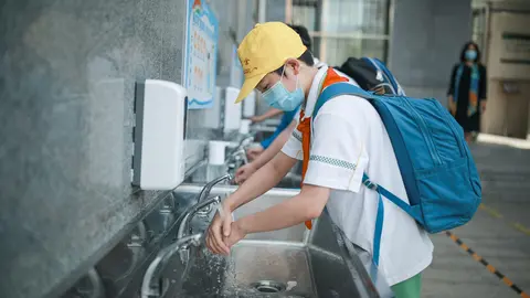 School students wash their hands at a school yard as thousands of students started returning to their classes after a long closure amid the coronavirus pandemic. Photo: -/TPG via ZUMA Press/dpa