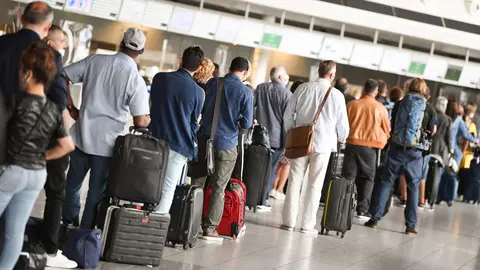 15 June 2020, Hessen, Frankfurt_Main: Passengers queue at Terminal 1 of Frankfurt Airport in front of a check-in counter after The travel ban for 27 European countries was lifted, which waas imposed due to the coronavirus pandemic. Photo: Arne Dedert/dpa
