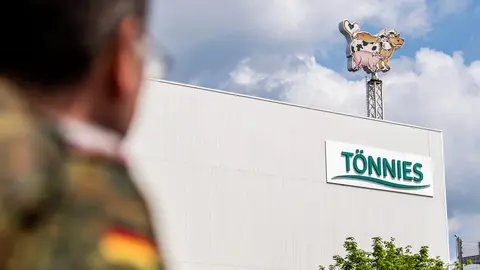 A soldier of the German Armed Forces looks at the logo of the Toennies meat factory, which had to halt operations after hundreds of employees at the family owned business had contracted coronavirus. Photo: David Inderlied/dpa
