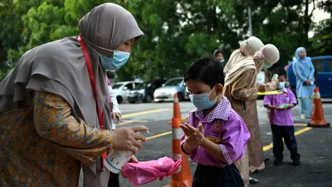 Teachers take body temperature and sanitize students' hands before entering Islamic Kindergarten MAIWP Sumayyah of Queen Lake City, after reopening amid the spread of the coronavirus pandemic. Photo: Zulaikha Zainuzman/BERNAMA/dpa