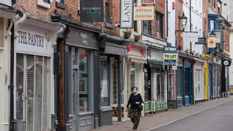 England, Leicester: A woman wearing a face mask walks in front of closed shops at a deserted street where localised coronavirus lockdown restrictions have been in place since 29 June, people were urged not to travel in or out of the area. Photo: Joe Giddens/PA Wire/dpa