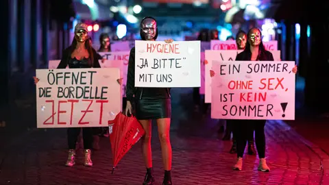 28 July 2020, Hamburg: Sex workers hold signs and placards during a demonstration in Herbertstrasse against the lockdown of the brothels due to the spread of the coronavirus (COVID-19) pandemic. Photo: Daniel Reinhardt/dpa