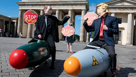30 July 2020, Berlin: Two activists disguised as US President Donald Trump and Russian President Vladimir Putin ride two models of nuclear bombs in front of the Brandenburg Gate during a demonstration for a world without nuclear weapons. Photo: Fabian Sommer/dpa