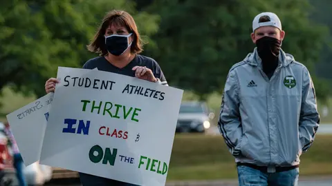 04 August 2020, US, Copley: A woman holds a placard during the Students, parents, and staff of Copley-Fairlawn City Schools protest outside the school board office shortly before a vote set to decide the future of learning due to concerns over Coronavirus (Covid-19). Photo: Andrew Dolph/dpa.