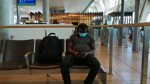 A man wearing a face mask waits at Oslo airport to board a flight to Helsinki. Photo: Foreigner.fi.