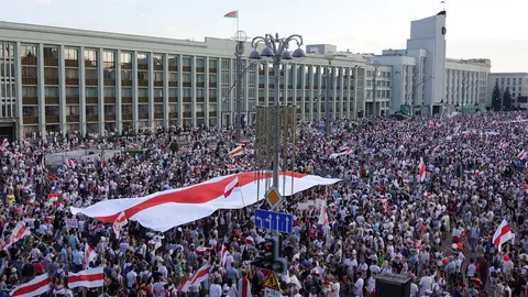 16 August 2020, Belarus, Minsk: People carry the historical Belarusian flag during a protest against Belarusian President Alexander Lukashenko at Independence Square. Photo: Ulf Mauder/dpa
