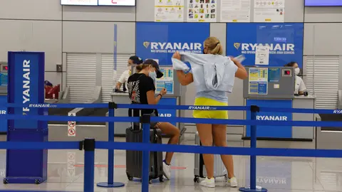 18 August 2020, Spain, Palma: Passengers wait in front of Ryanair check-in desk at Palma de Mallorca Airport. Germany has declared nearly all of Spain, including the island of Mallorca, as risky areas following a spike of coronavirus cases. Photo: Clara Margais/dpa