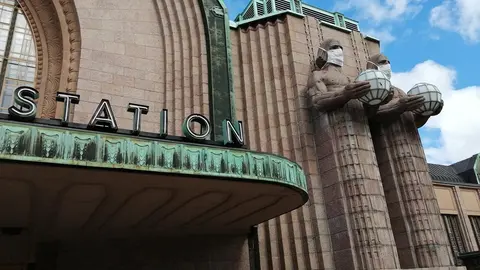 A view of Helsinki's central station, with the stone men who guard the entrace equipped with face masks. Photo: Foreigner.fi.