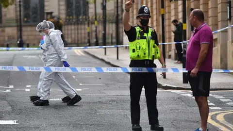 06 September 2020, England, Birmingham: Forensic officers walk past a policeman directing a member of the public, inside the cordoned area on Barwick Street in Birmingham after a number of people were stabbed in the city centre. West Midlands Police said they were called to reports of a stabbing at around 12.30am on Sunday and a number of other stabbings were reported in the area at around the same time. Photo: Jacob King/dpa.