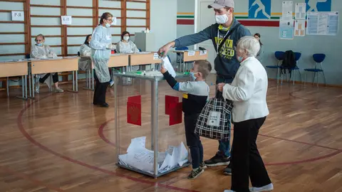 12 September 2020, Russia, Tambow: A small child wearing a face mask casts his father's vote in a ballot box at a polling station during the 2020 Regional elections. Photo: Lev Vlasov/dpa.