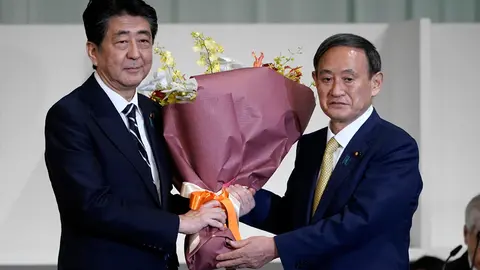 14 September 2020, Japan, Tokio: Japanese Prime Minister Shinzo Abe (L), presents a bouquet of flowers to Yoshihide Suga, newly elected leader of Japan's ruling Liberal Democratic Party (LDP). Suga was elected leader of Japan's governing Liberal Democratic Party on Monday, paving the way for him to become the country's next prime minister. Photo: Pool/dpa.