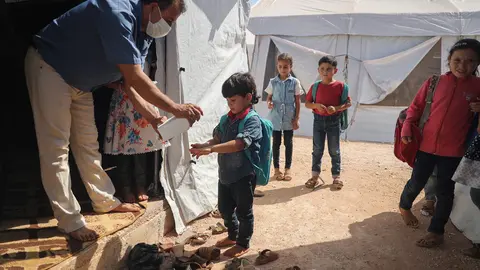 27 September 2020, Syria, Idlib: A teacher disinfects a child hands at a school in the town of Batenta camp in Idlib governorate on the first day of the school year, amid the spread of the coronavirus. Photo: Anas Alkharboutli/dpa.