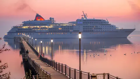 FILED - The cruise liner "Europa" passes the pier in Wismar-Wendorf in the early morning on its way to the harbour. In its latest effort to put some wind in the sails of a tourism sector left high and dry by the coronavirus pandemic, Singapore will from next month permit cruise ships to sail, for the first time since March. Photo: Jens Büttner/dpa.