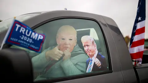 10 October 2020, US, Martinsville: A man wears a mask of US President Donald Trump during cars parade to support Trump. Photo: Jeremy Hogan/dpa.