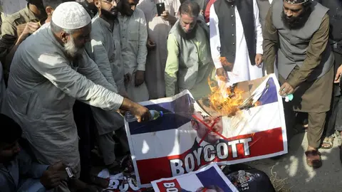 27 October 2020, Pakistan, Karachi: Pakistani demonstrators burn a banner depicting French President Emmanuel Macron on the French flag, during a protest against Macron&#39;s comments on Islam&#39;s prophet Muhammad cartoons. Photo: Ppi/dpa.