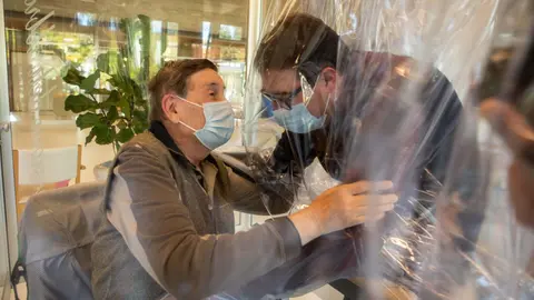 11 November 2020, Italy, Castelfranco Veneto: A resident (L) of the Domenico Sartor nursing home in Castelfranco Veneto embraces a visiting relative through a protective plastic sheet in a so-called "Hug Room" amid the new coronavirus pandemic. Photo: Filippo Ciappi/LaPresse via ZUMA Press/dpa