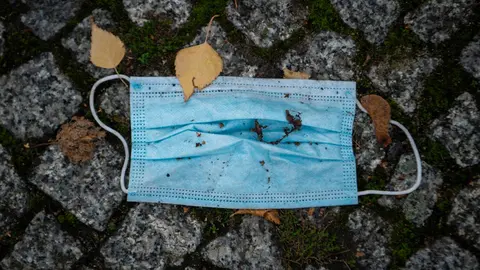 19 November 2020, Berlin: A face mask covered with some autumn leaves lies on the sidewalk. Public life in Germany has been brought to a near-standstill as part of a four-week shutdown in Europe's largest economy in a bid to stem a surge in coronavirus infections. Photo: Kira Hofmann/dpa-Zentralbild/dpa