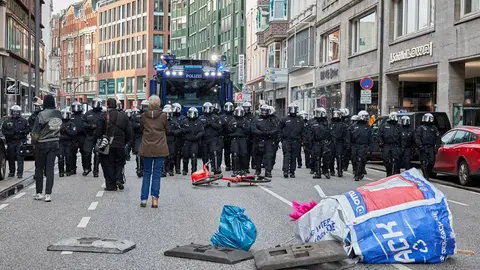 22 November 2020, Hamburg: Police officers run in the form of a police chain in front of a water cannon as protesters set up their barricades during a protest against the measures of the German government amid the coronavirus pandemic. Photo: Georg Wendt/dpa
