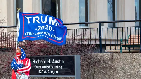 23 November 2020, US, Lansing: A supporter of US President Donald Trump waves a flag outside the Michigan Secretary of State office during the Michigan Board of State Canvassers meeting. The board subsequently certified the results of the 2020 presidential election, which showed Joe Biden ahead of President Trump by about 150,000 votes. Photo: Jim West/ZUMA Wire/dpa.