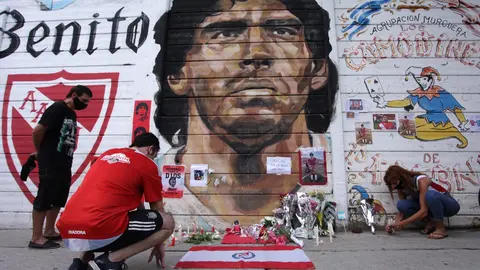 25 November 2020, Argentina, Buenos Aires: People place flowers and candles in front of a mural depicting the Argentinian legend Diego Mardona outside the Argentinos Juniors football club, where Maradona started his career. Argentina football great Diego Maradona has died at the age of 60, the Argentinian Football Association said on Wednesday. Photo: Carol Smiljan/ZUMA Wire/dpa.