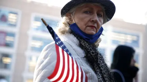 29 November 2020, US, New York: A protester holds an American Flag during a rally in Union Square Park against coronavirus lockdown. Photo: John Lamparski/SOPA Images via ZUMA Wire/dpa