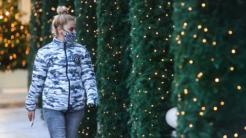 A woman wears a face mask passes in front of Christmas lights outside shops at Oxford Street while England continues a four week national lockdown to curb the spread of coronavirus. Photo: Kirsty O'connor/PA Wire/dpa