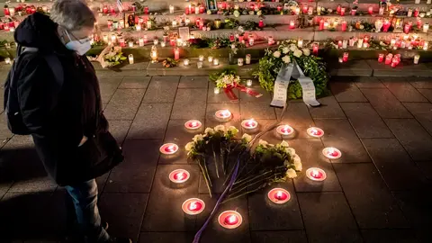 19 December 2020, Berlin: A woman wears a face mask looks at the candles and white roses laid in the shape of a heart at the "Golden Rift" memorial during the commemoration on the fourth anniversary of the Islamist attack on the Breitscheidplatz Christmas market. where On 19 December 2016, a truck was deliberately driven into the Christmas market next to the Kaiser Wilhelm Memorial Church at Breitscheidplatz in Berlin, leaving 12 people dead and 56 others injured. Photo: Christoph Soeder/dpa