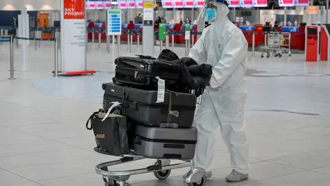21 December 2020, Czech Republic, Prague: A passenger is seen wearing full protective equipment as he walks with his luggage at Vaclav Havel Airport Prague. The Czech Republic has announced an immediate ban on flights from and to Britain over the recently discovered variant of the coronavirus. Photo: Vít imánek/CTK/dpa
