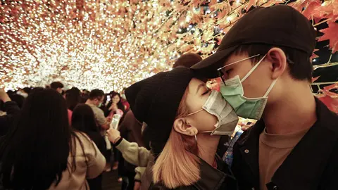 18 December 2020, Taiwan, New Taipei City: A couple wear face masks as they kiss in an autumn leaves decoration at the foot bridge before the Christmas. Photo: Daniel Ceng Shou-Yi/ZUMA Wire/dpa