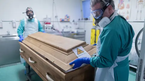 FILED - Christoph Kuckelkorn (r), funeral director and president of the Cologne Carnival Festival Committee, and an employee close a coffin containing a deceased person who died of or with the coronavirus. Both wear protective suits and respirators. For Kuckelkorn, the corona pandemic is palpable. "We have perceptibly a significant increase in corona deaths," Kuckelkorn told the German Press Agency. Photo: Rolf Vennenbernd/dpa