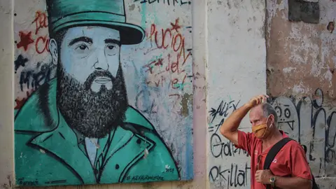 FILED - A man with a mouth-and-nose guard walks in front of a mural of former Cuban President Fidel Castro. In Cuba, 5310 people have contracted Covid-19. Photo: Guillermo Nova/dpa
