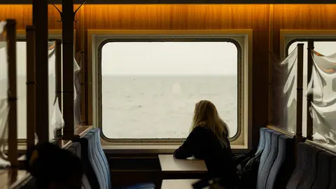 dpatop - 22 February 2021, Lower Saxony, Norderney: A woman sits at a window of the ship during the crossing with the North Sea ferry Frisia from Norddeich to Norderney and looks at the North Sea (to dpa "Tourism figures 2020 for Lower Saxony). Photo: Mohssen Assanimoghaddam/dpa