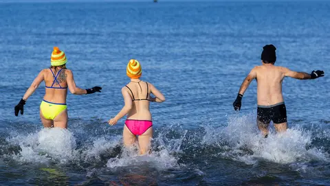 21 February 2021, Mecklenburg-Western Pomerania, Warnemuende: Members of the ice-bathing club "Rostocker Seehunde" run for a swim in the Baltic Sea on the beach of Warnemuende. Photo: Jens Büttner/dpa-Zentralbild/dpa