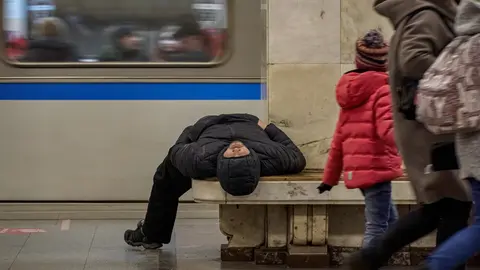 21 March 2021, Russia, Moscow: People walks past a man sleeping on a bench at a metro station near the Izmailovo Kremlin center. Photo: Mihail Tokmakov/SOPA Images via ZUMA Wire/dpa.