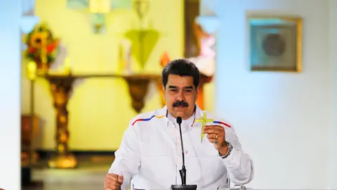 HANDOUT - 28 March 2021, Venezuela, Caracas: Nicolas Maduro, president of Venezuela, holds a cross during a press conference. Maduro has offered to swap oil for COVID-19 vaccines in view of rapidly rising coronavirus numbers as well as US sanctions against the crisis-torn South American state. Photo: Jhonn Zerpa/Prensa Miraflores/dpa - ATTENTION: editorial use only and only if the credit mentioned above is referenced in full