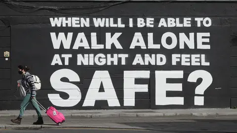 29 March 2021, Ireland, Dublin: A woman walks past the latest mural by Irish artist Emmalene Blake in Dublin city center, which is related to violence against women in the wake of the death of Sarah Everard. Photo: Niall Carson/PA Wire/dpa