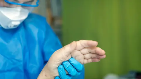 A Finnish medic holds the hand of a sick elderly person in the Helsinki hospital. Photo: @HUS.