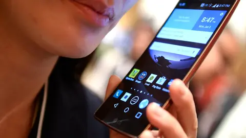 FILED - 05 January 2015, US, Las Vegas: A visitor holds an LG G Flex 2 smartphone at the consumer electronics show CES 2015. The South Korean electronics manufacturer LG is closing its loss-making mobile phone business. Photo: picture alliance / dpa