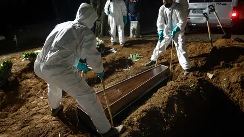 02 April 2021, Brazil, Sao Paulo: Employees of the Vila Formosa cemetery, the largest in Latin America, carry a coffin to bury a person who died of coronavirus (Covid-19). Due to the high number of deaths, the employees also work during the night. Photo: Lincon Zarbietti/dpa